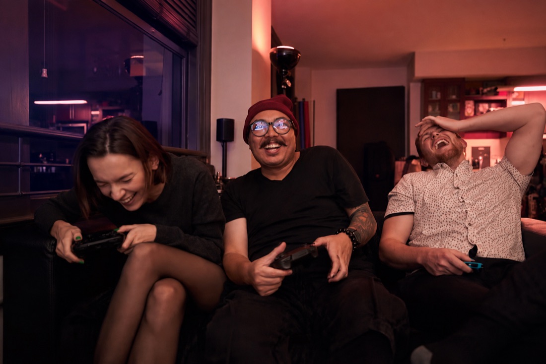 Friends laughing together while playing video games at home